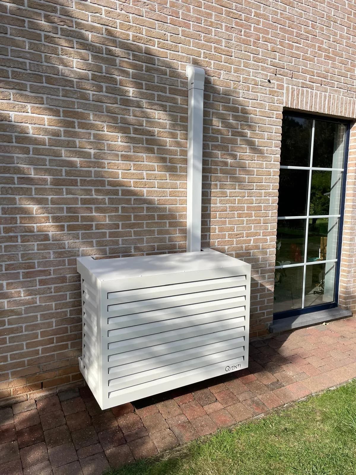 Airco buitenunit in witte omkasting tegen de gevel